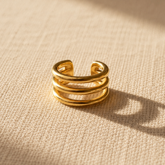Goldener Intreccio Ear Cuff auf beigem Leinenstoff.