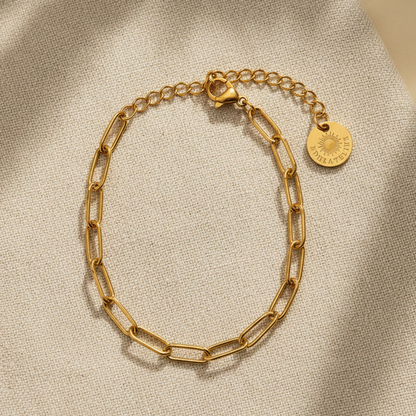 Linea Gliederarmband goldfarben auf hellem Leinenstoff mit warmem Schatten.
