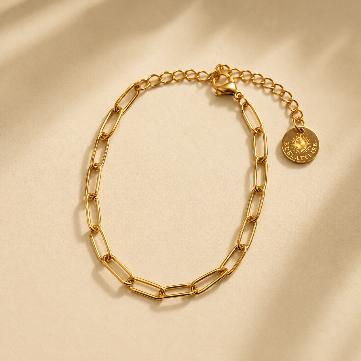 Linea Gliederarmband goldfarben auf hellem warmbeigen Hintergrund mit leichtem Schatten.