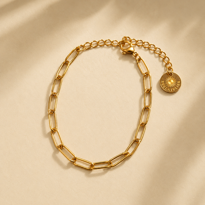 Linea Gliederarmband goldfarben auf hellem warmbeigen Hintergrund mit leichtem Schatten.