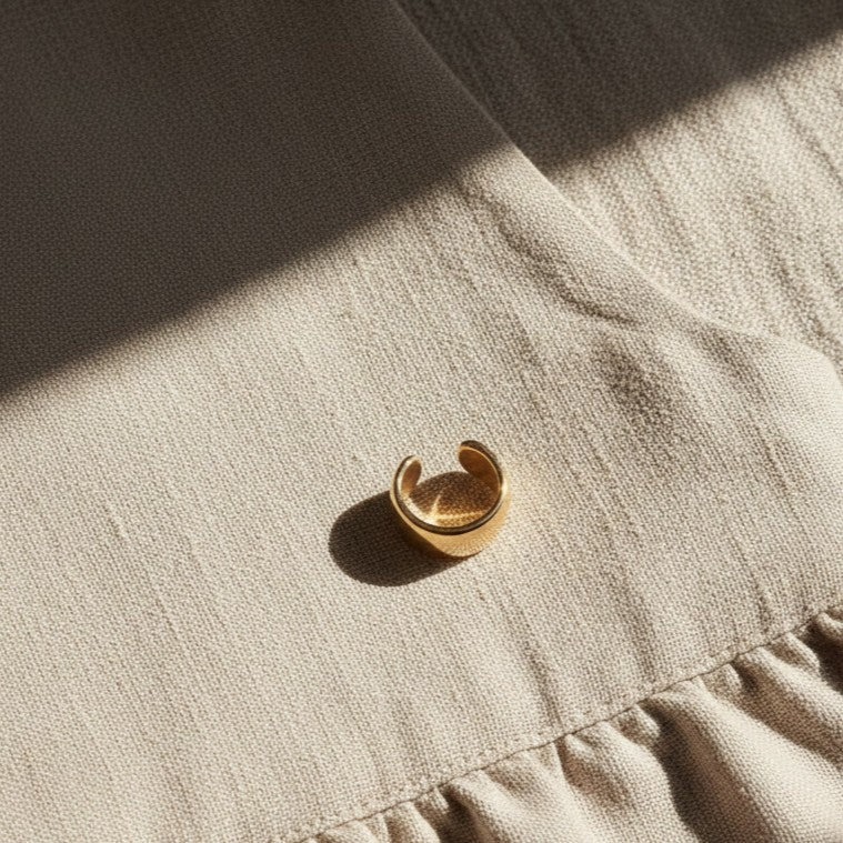 Goldener Luna Ear Cuff auf hellem Leinenstoff.