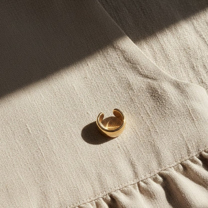 Goldener Luna Ear Cuff auf hellem Leinenstoff.
