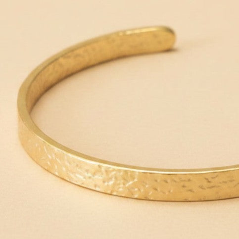 Detailaufnahme vom goldfarbenen Martella Armreif mit gehämmerter Oberfläche.