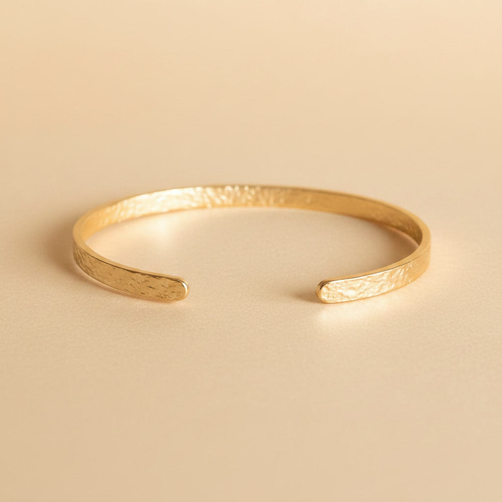 Offener goldfarbener Martella Armreif mit gehämmerter Oberfläche.
