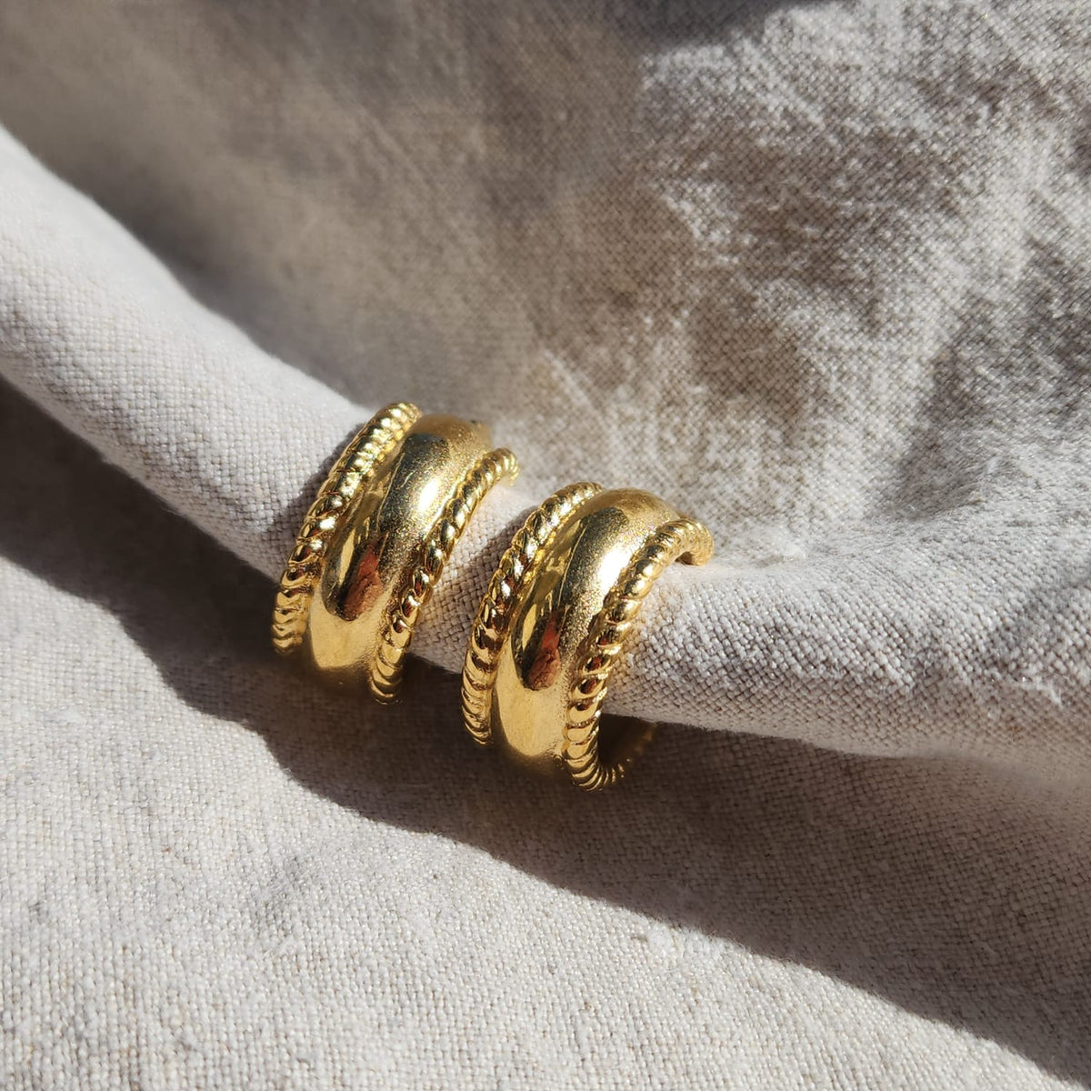 Ornella Chunky Creolen Gold mit breiter gewölbter Form und dekorativen Kordelrändern in Detailansicht.