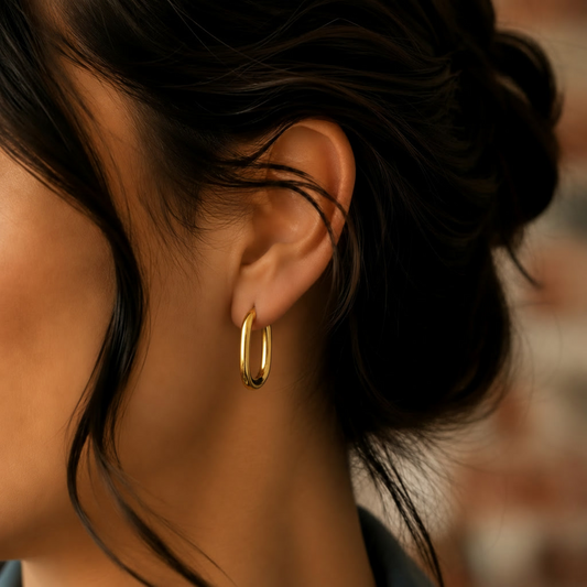 Model trägt kleine goldene ovale Creolen und goldene Kette im warmen Tageslicht