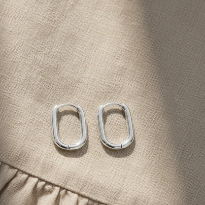Model trägt silberfarbene ovale Edelstahl-Creolen, zeitloser minimalistischer Schmuck.