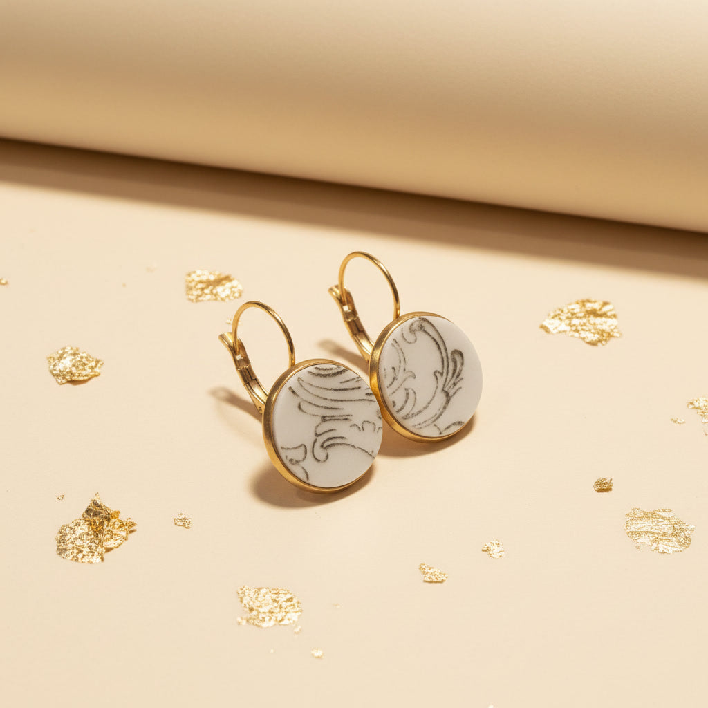 Seitenansicht der runden Porzellanohrringe Ornamenta von EDELATELIER. Die Upcycling-Ohrhänger zeigen ein historisches grafisches Dekor auf weißem Porzellan in einer edlen Gold-Optik-Einfassung.