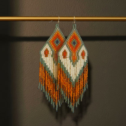 Handgefertigte Statement-Ohrringe mit geometrischem Perlenmuster aus japanischen Miyuki Delica Perlen in Orange, Weiß, Grün und Gold sowie langen Perlenfransen vom Edelatelier.