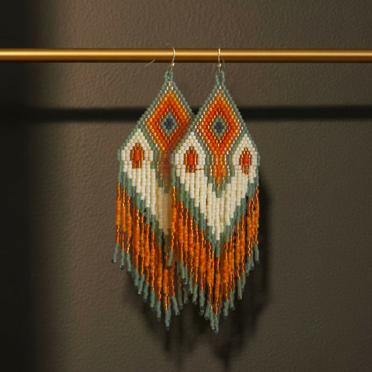 Handgefertigte Statement-Ohrringe mit geometrischem Perlenmuster aus japanischen Miyuki Delica Perlen in Orange, Weiß, Grün und Gold sowie langen Perlenfransen vom Edelatelier.