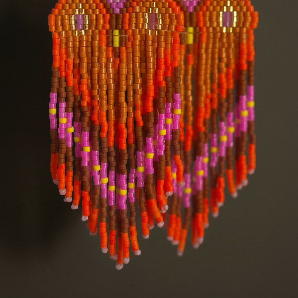Detaillierte Makroaufnahme des handgewebten Rautenmusters der Ohrringe Riva Ardente von EDELATELIER. Das präzise geometrische Design aus Miyuki-Perlen kombiniert Pink-, Orange- und Brauntöne zu einer feurigen Komposition.