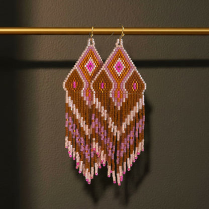 Handgewebte Miyuki Perlenohrringe Modell Rosa Cannella von EDELATELIER. hängend an einer goldenen Halterung; das geometrische Muster kombiniert warme Brauntöne mit leuchtendem Pink bei einer Länge von 9,5 cm.