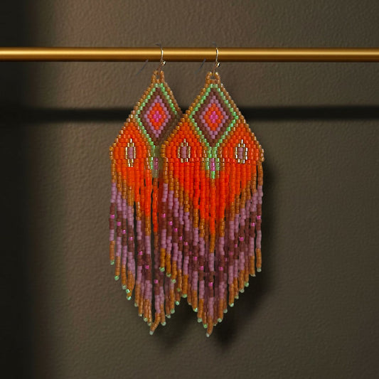 Ein Paar handgefertigte Statement-Ohrringe Modell Rosa di Selva von EDELATELIER, präsentiert an einer goldenen Stange. Die ca. 10 cm langen Ohrringe zeigen ein leuchtendes Muster in kräftigem Orange und warmem Braun, kombiniert mit kontrastreichen Akzenten in Pink, Flieder und einem frischen Akzent-Grün.