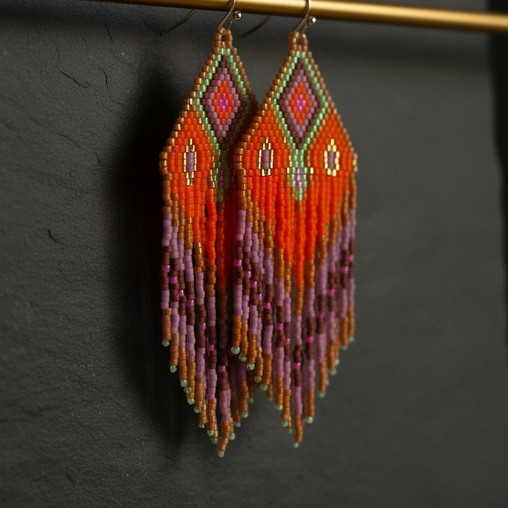 Seitliche Nahaufnahme der handgefertigten Statement-Ohrringe Rosa di Selva von EDELATELIER. Der Fokus liegt auf der filigranen Struktur der Miyuki-Perlen in leuchtendem Orange und Pink, während der weiche Fall der Fransen die Dynamik und Leichtigkeit des Designs unterstreicht.