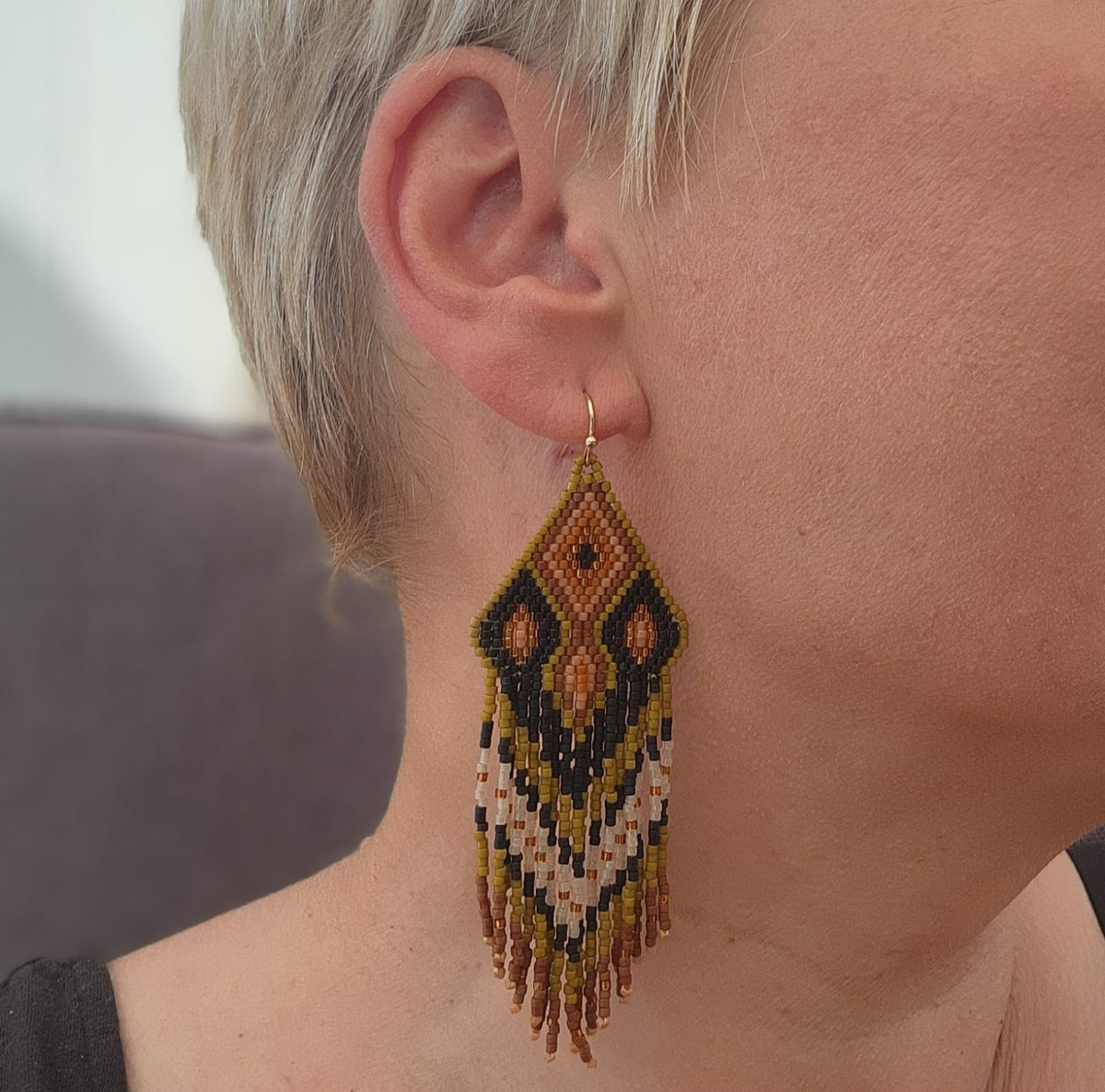Savana Nera Miyuki Ohrring am Ohr getragen, langer handgewebter Statement Ohrring mit geometrischem Boho-Muster.