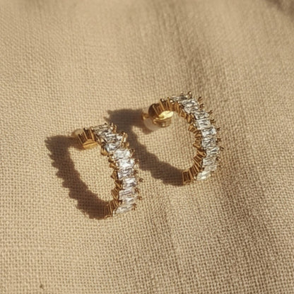 Scintilla Zirkonia Creolen in Gold auf hellem Leinenstoff mit warmem Licht und Schatten.