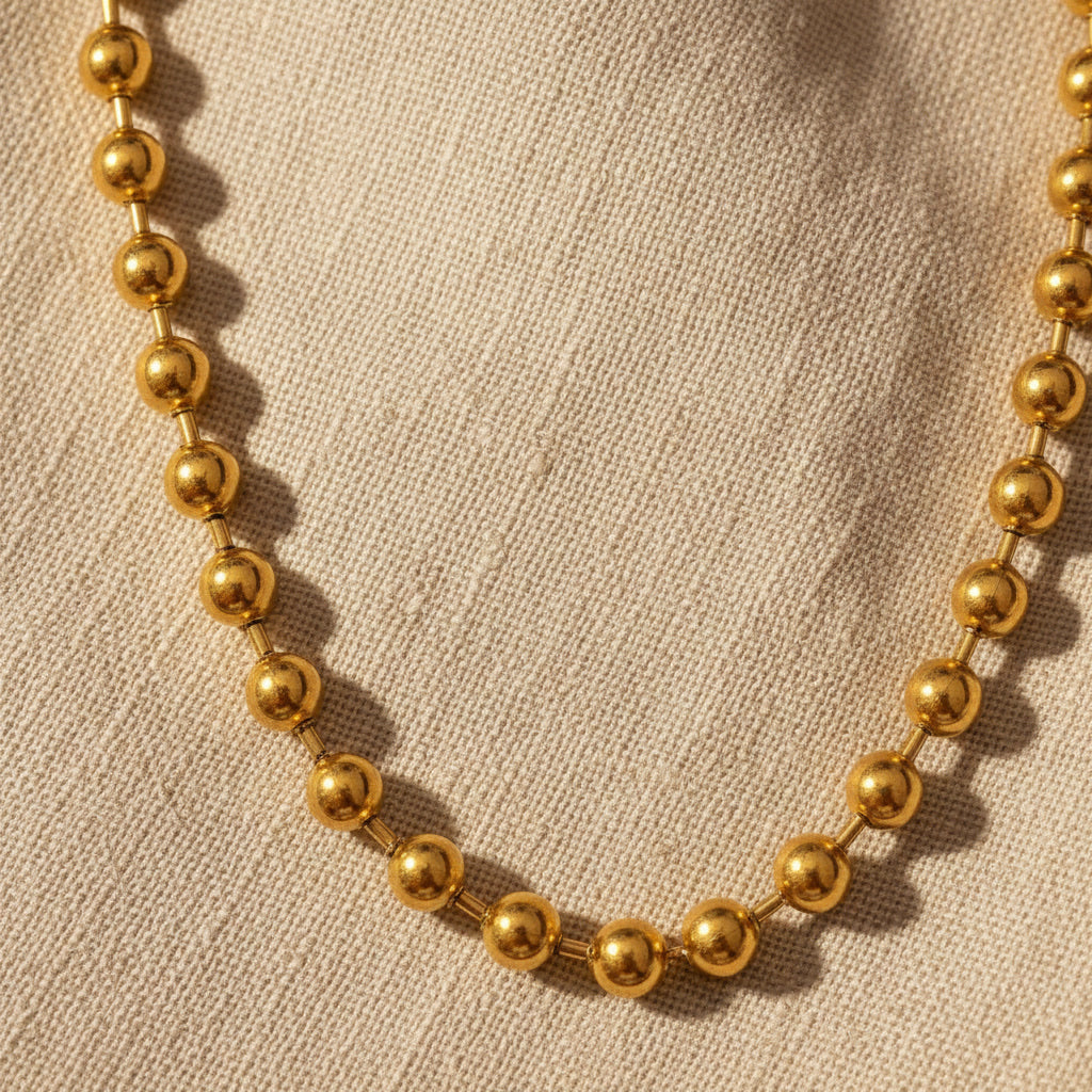 Detailaufnahme der goldfarbenen Sfera Halskette mit Kugelstruktur.