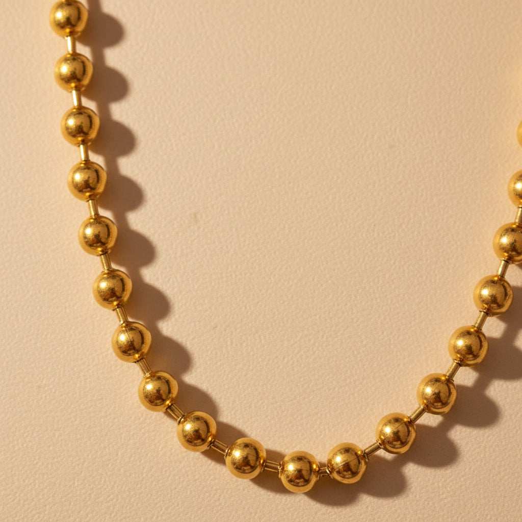 Detailaufnahme der goldfarbenen Sfera Halskette mit Kugelstruktur.