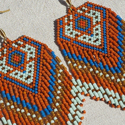 Tangeri Miyuki Statement Ohrringe schräg auf Leinen, geometrisches Muster aus japanischen Delica-Perlen sichtbar.