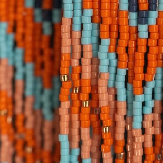 Detailansicht der hängenden Perlenfransen des Ohrrings Terra e Mare von EDELATELIER. Die vertikalen Reihen aus orangefarbenen, meerblauen und goldfarbenen Miyuki-Perlen zeigen die feine Textur der Handarbeit und die hochwertige Verarbeitung der 10 cm langen Statement-Ohrringe.
