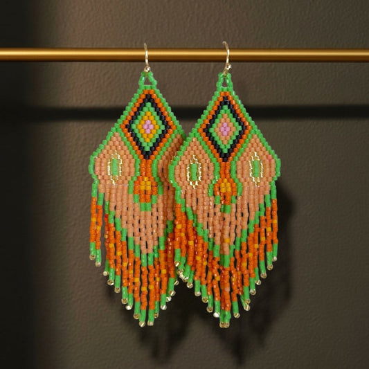 Handgewebte Miyuki Perlenohrringe Modell Tramonto Etrusco von EDELATELIER., dekorativ hängend an einer horizontalen goldenen Metallstange. Das geometrische Muster in Blattgrün, Terrakotta und Mauve sowie die feinen Fransen betonen die filigrane Handarbeit und die Länge von 8,5 cm.