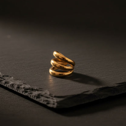 Treccia Ear Cuff Gold aus Edelstahl in seitlicher Ansicht auf dunklem Stein.